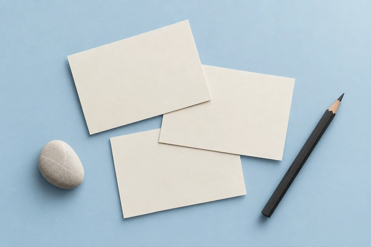 Blank cards and pencil arranged on a seamless blue background